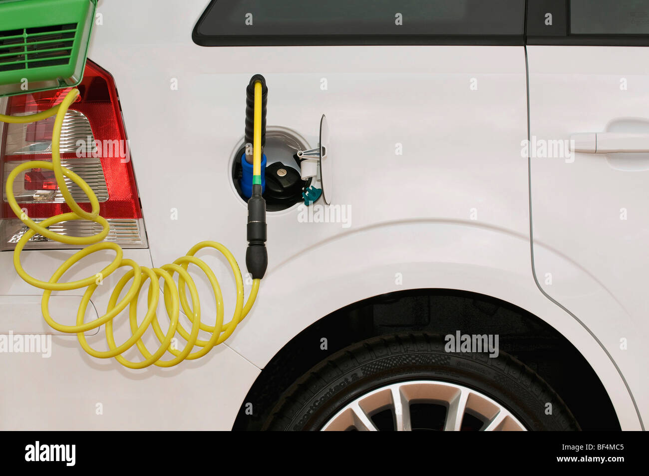 Il rifornimento di un'auto con un ugello di gas accanto ad un convenzionale tappo benzina Foto Stock