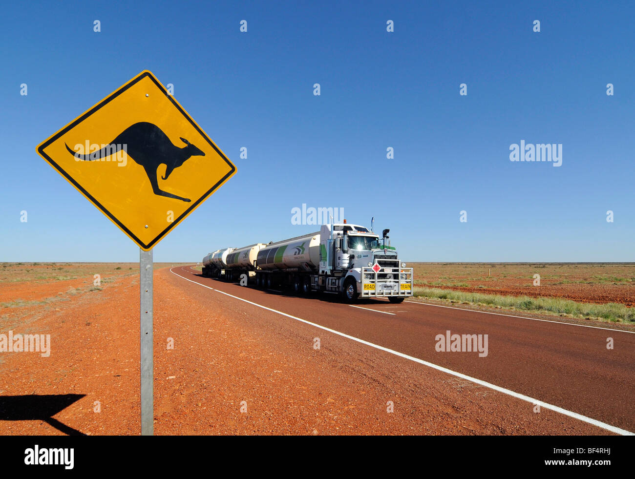 Un treno su strada passando da un canguro cartello stradale nell'outback australiano. Foto Stock