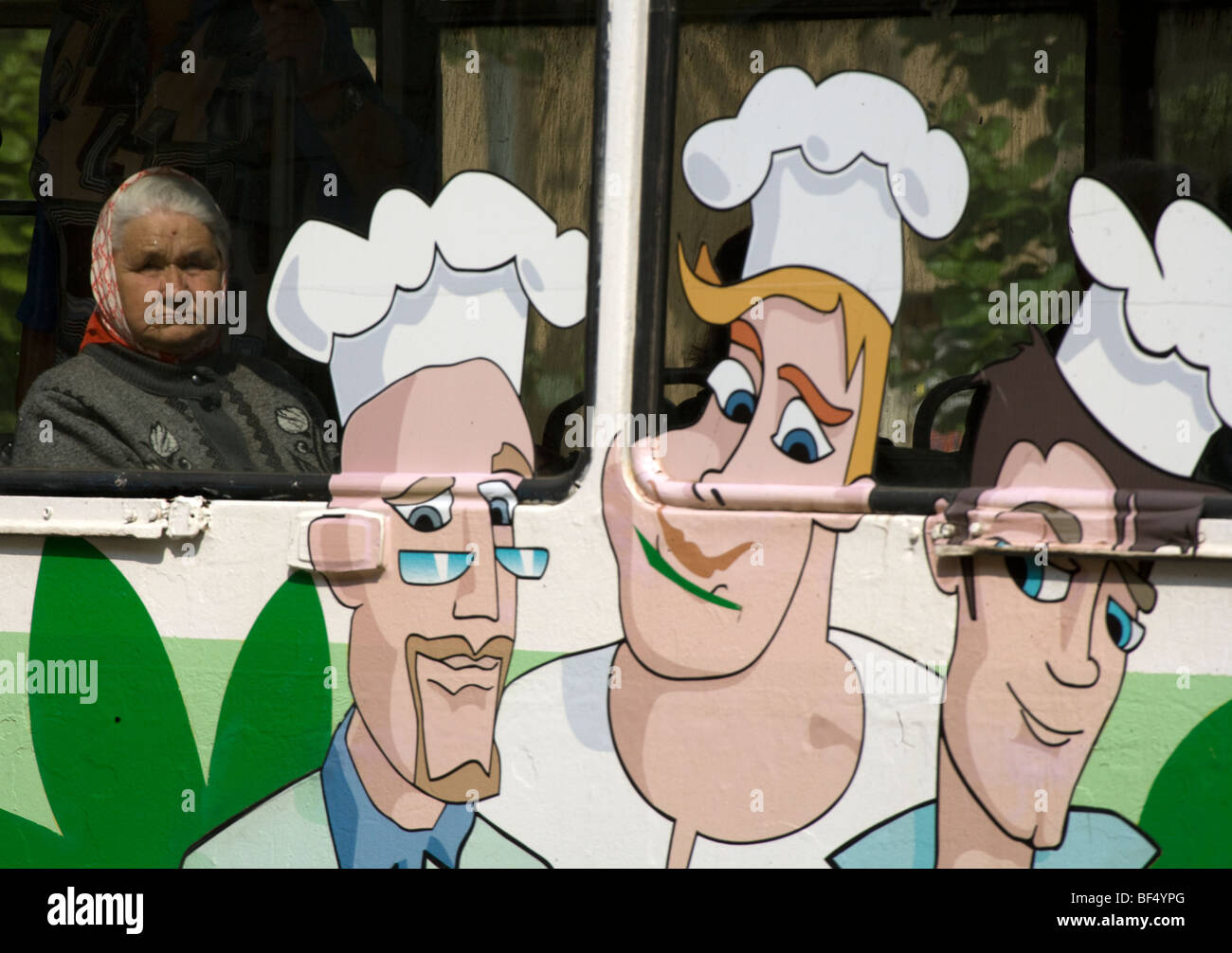 Donna che guarda attraverso la finestra del tram con il cartoon chef annuncio, Ekaterinburg, Russia Foto Stock