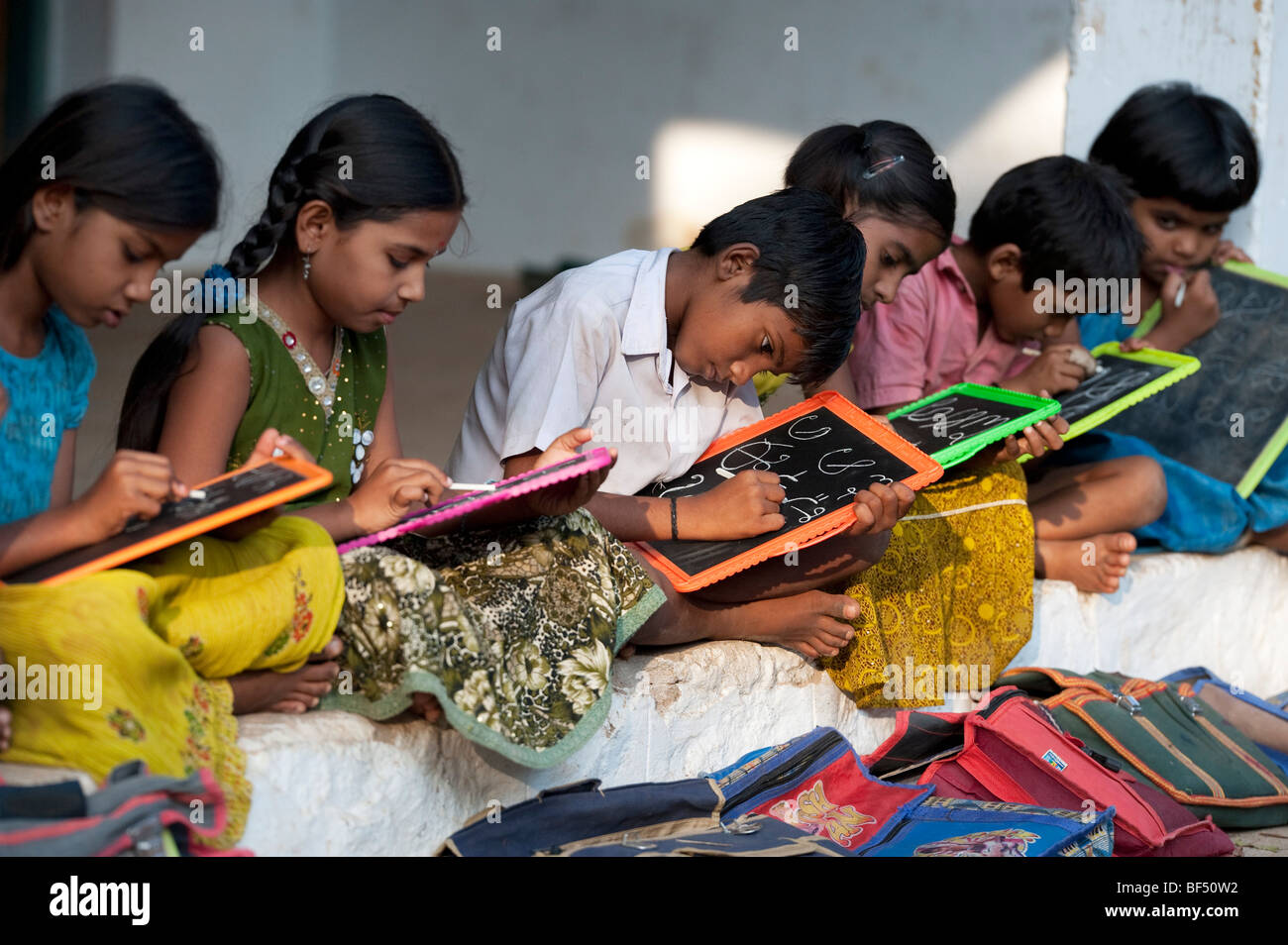 Indian School bambini seduti al di fuori della loro scuola scrivere sulle lavagne. Andhra Pradesh, India Foto Stock