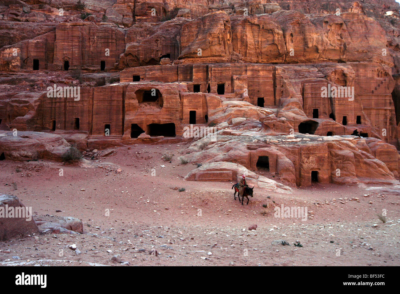 Un beduino cavalca il suo cavallo davanti alle tombe sulla strada delle facciate, Petra, Giordania Foto Stock
