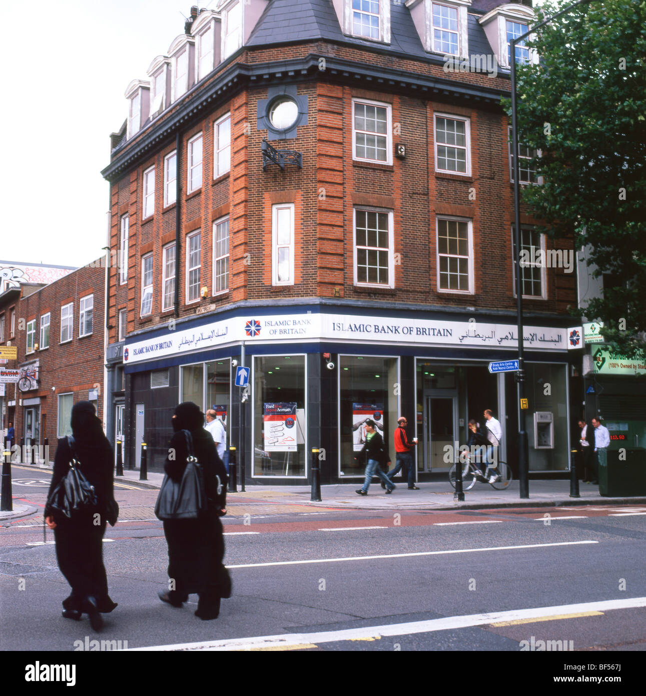 Due giovani donne Musulmane di indossare nero tradizionale traversata burqas Whitechapel High Street vicino a banca islamica in East London REGNO UNITO KATHY DEWITT Foto Stock