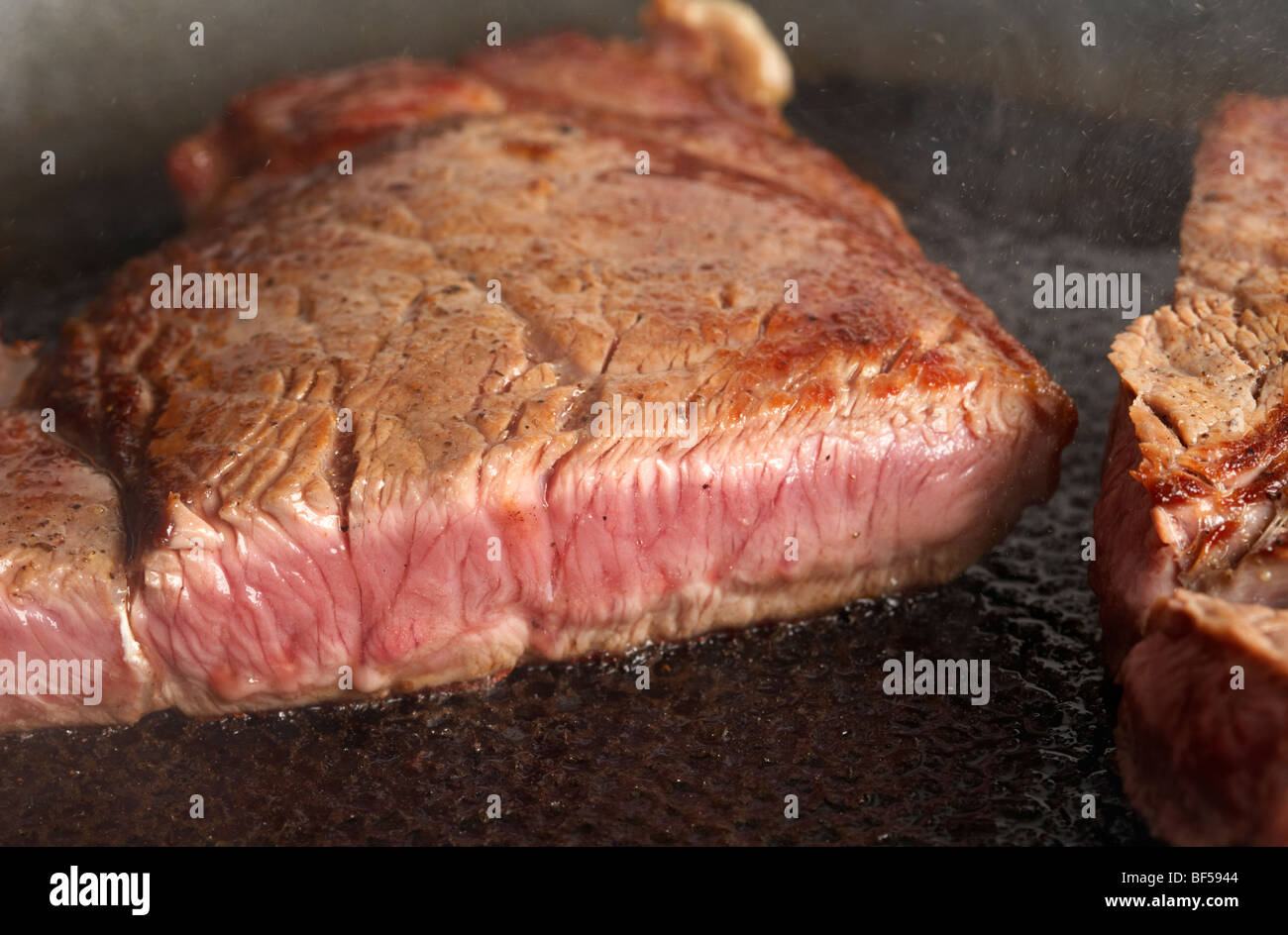 Fetta di mezzo raro chump steak di organic longhorn vacche irlandese friggere in una padella Foto Stock