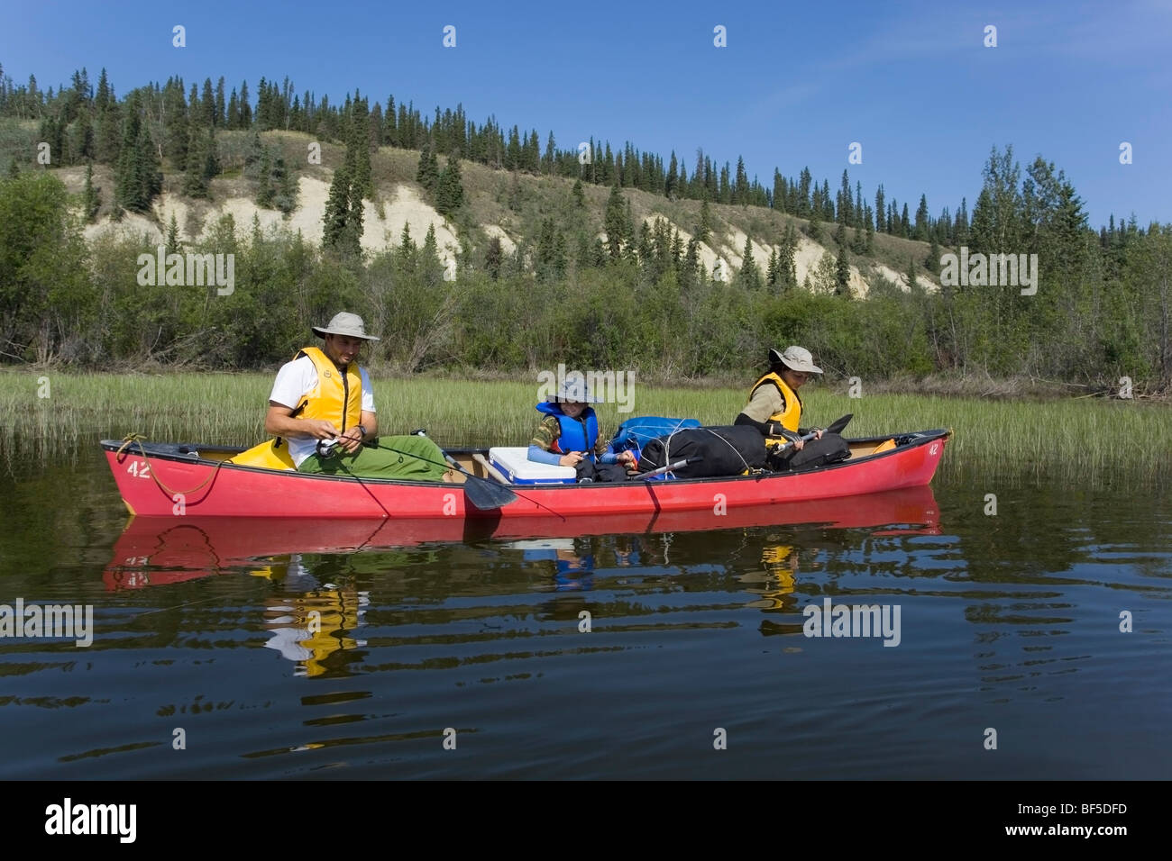 Famiglia con giovane ragazzo in una canoa, pesca, Teslin River, alta cut bank dietro, Yukon Territory, Canada Foto Stock