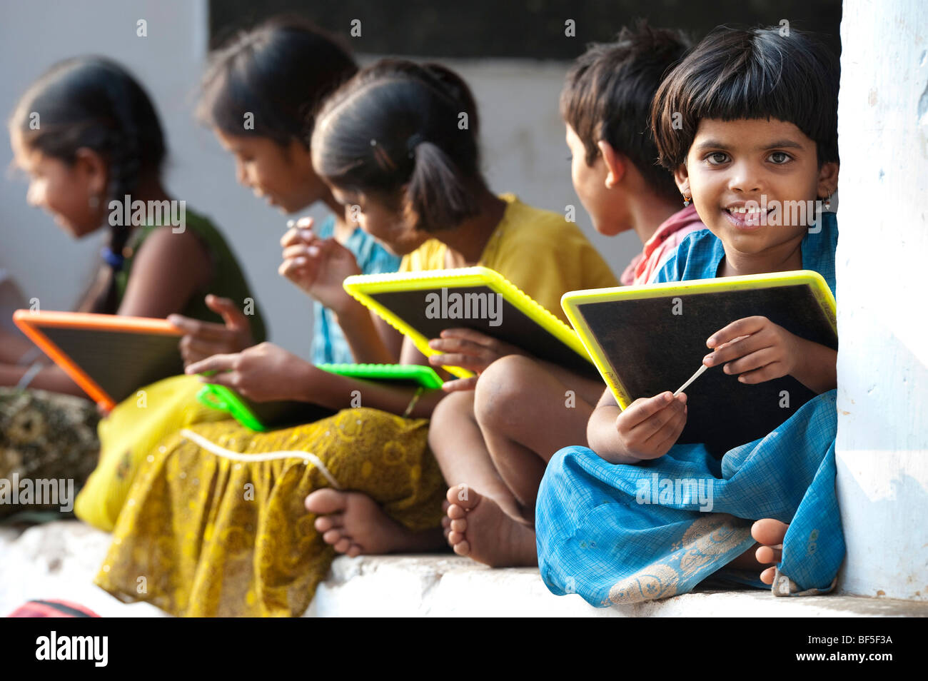 Indian School bambini seduti al di fuori della loro scuola scrivere sulle lavagne. Andhra Pradesh, India Foto Stock