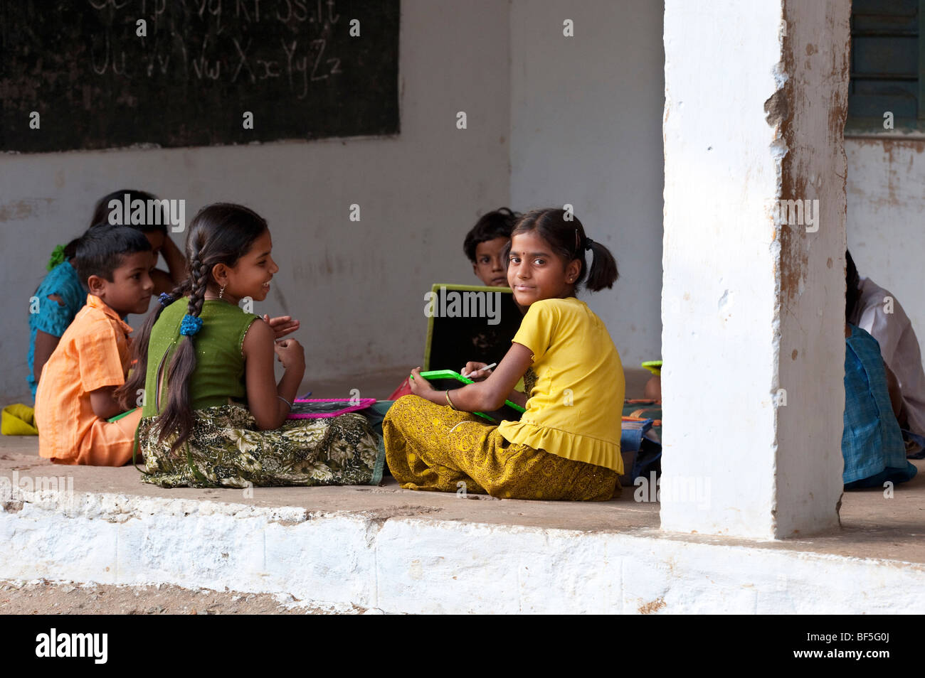 Indian School bambini seduti al di fuori della loro scuola scrivere sulle lavagne. Andhra Pradesh, India Foto Stock