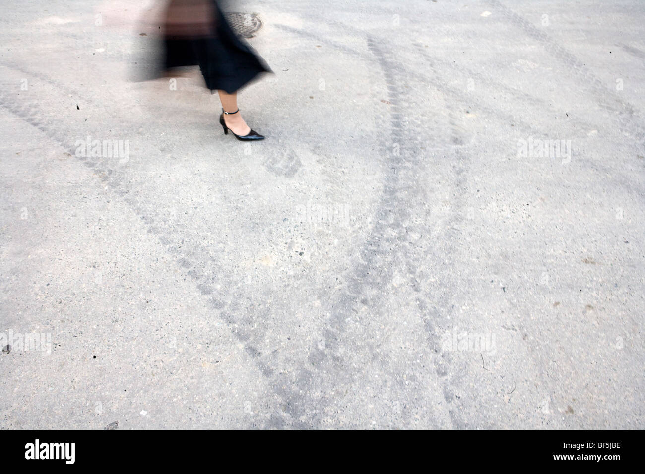 Sfocata cintura di movimento verso il basso vista della donna in gonna e tacchi alti camminando sulla strada Foto Stock