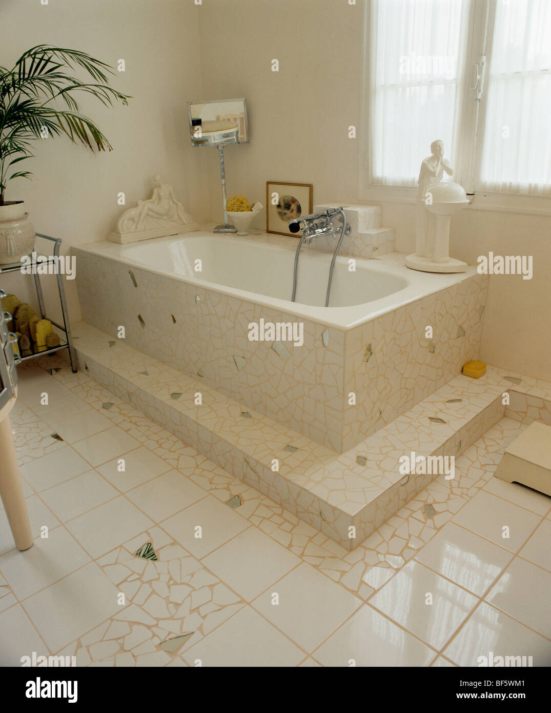 Bianco e a specchio con pavimento a mosaico e vasca da bagno surround degli  anni Trenta in stile con bagno con bagno sul pavimento rialzato Foto stock  - Alamy