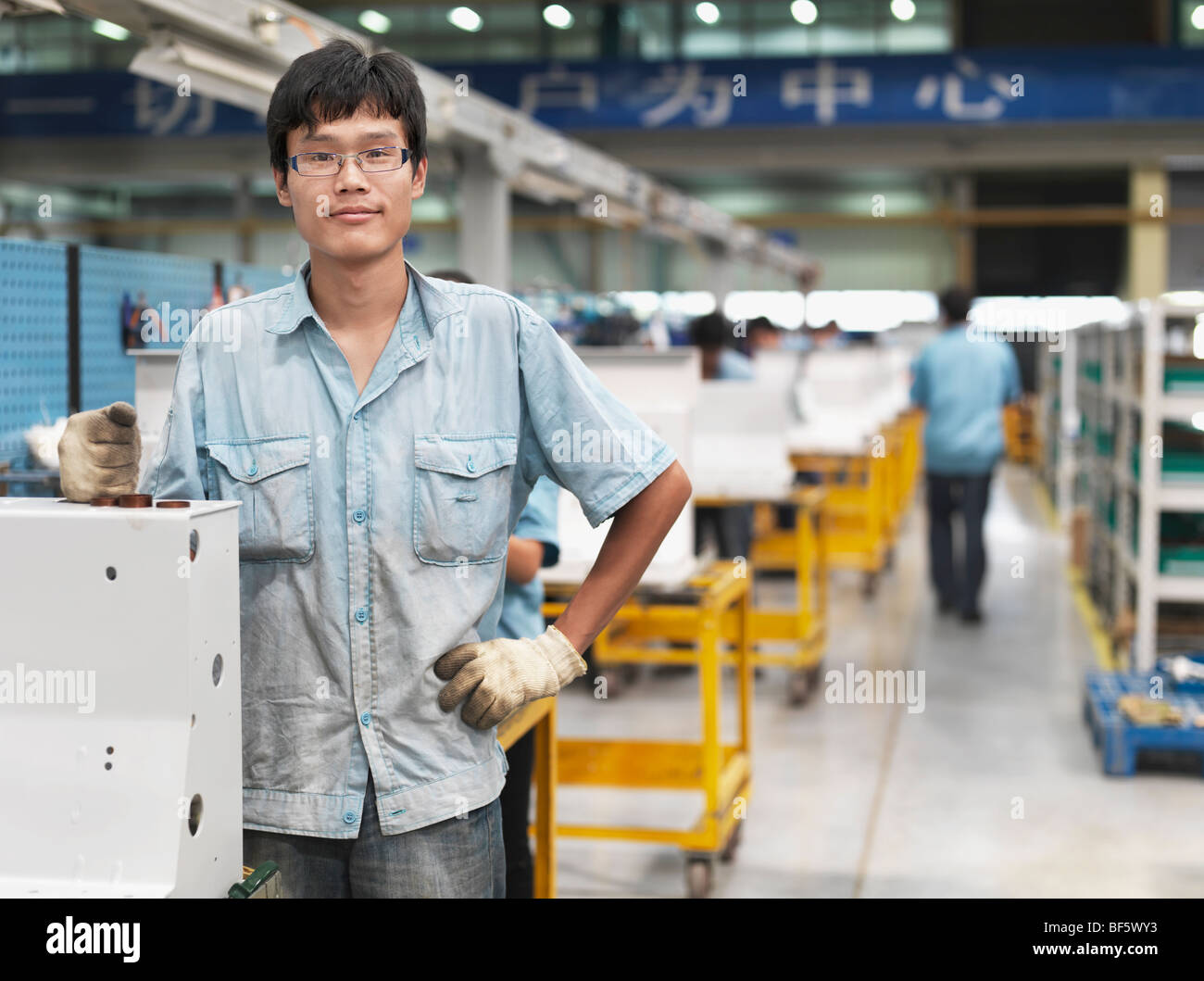 Un operaio di fabbrica che stava alla sua stazione di lavoro in linea di montaggio. Foto Stock