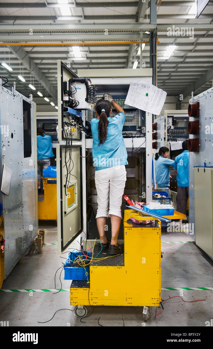 Un operaio di fabbrica l'installazione di una parte di un quadro elettrico in una linea di assemblaggio. Foto Stock