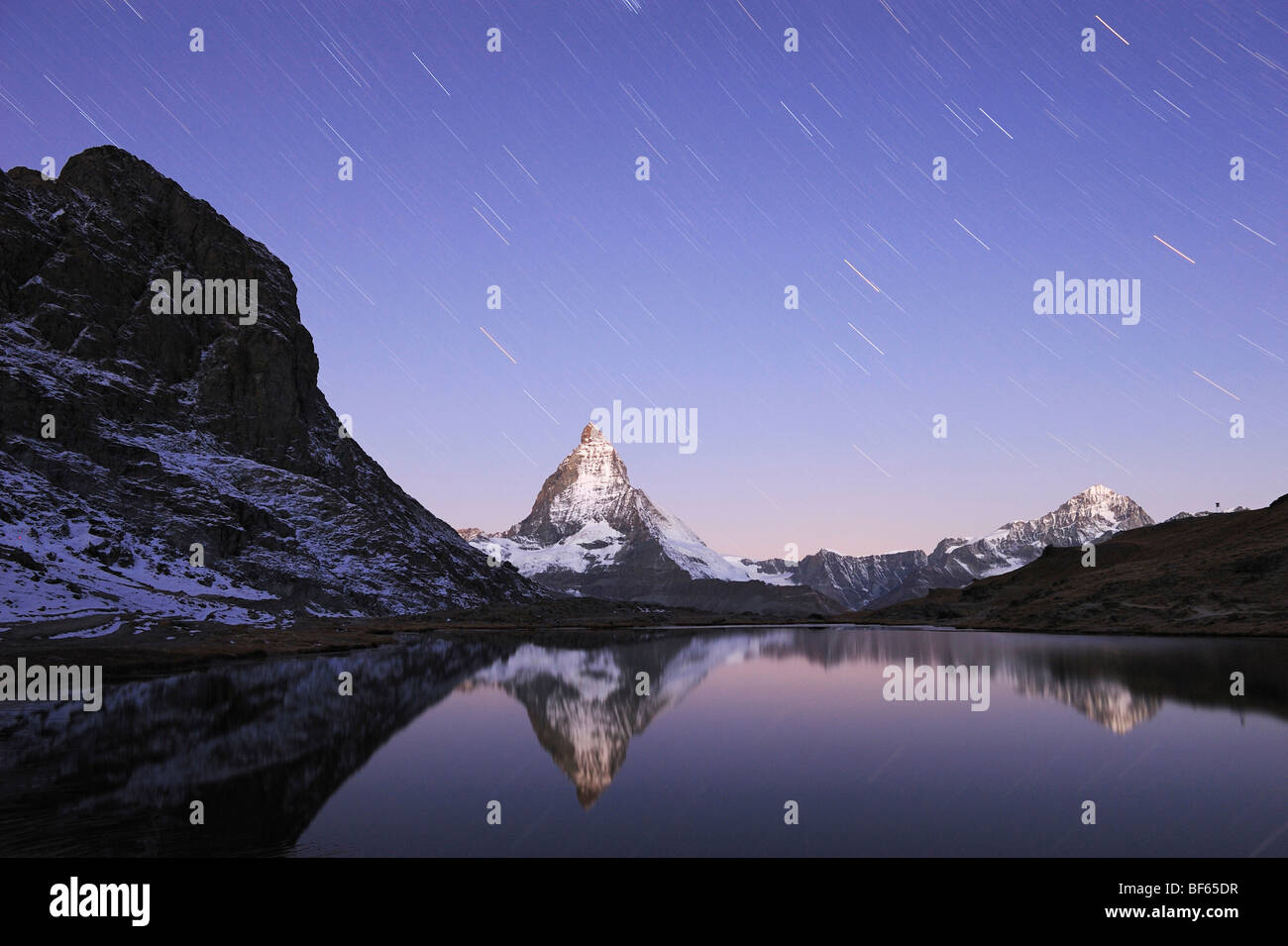 Il Cervino di notte con tracce stellari in inverno con la riflessione nel Riffelsee, Zermatt, Vallese, Svizzera, Europa Foto Stock