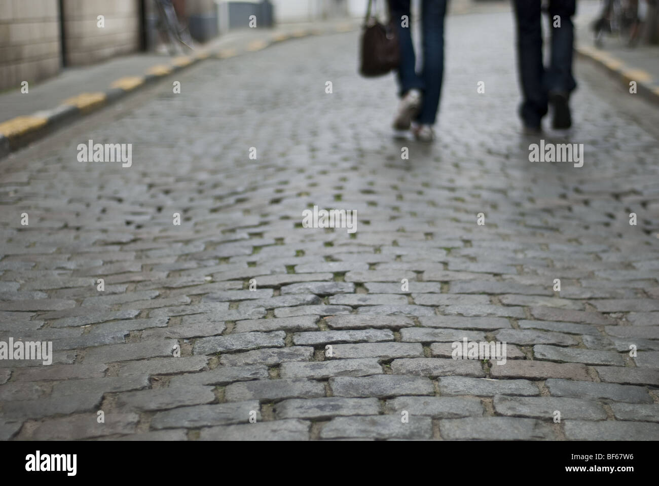 Due pedoni a piedi verso il basso una mattonella di pietra in strada di Lovanio, Belgio. Foto Stock