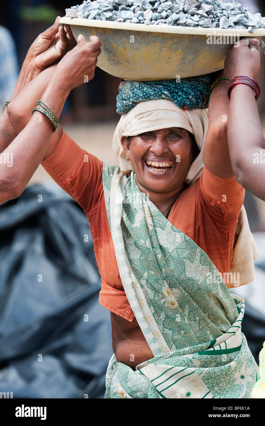 Donna indiana che lavora sulle strade, trasportando pietre in una ciotola sul suo capo. Puttaparthi, Andhra Pradesh, India Foto Stock