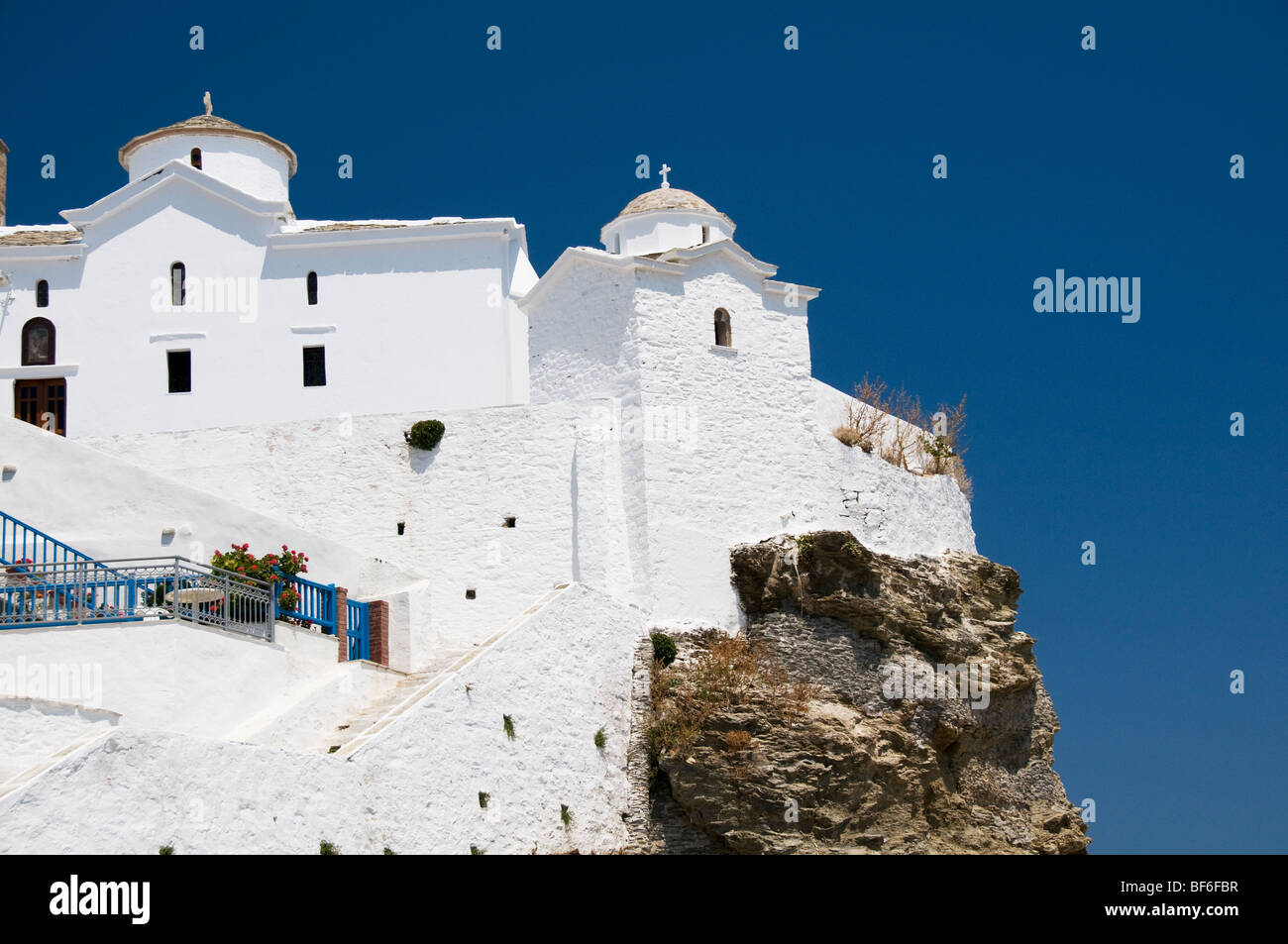 Imbiancati greco chiesa costruita sulla roccia affacciato sul mare nella città principale dell'isola greca di Skopelos, le Sporadi, Grecia Foto Stock