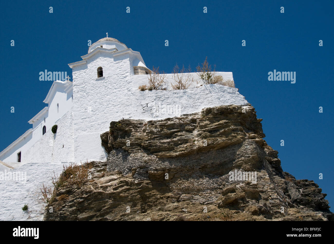 Imbiancati greco chiesa costruita sulla roccia affacciato sul mare nella città principale dell'isola greca di Skopelos, le Sporadi, Grecia Foto Stock