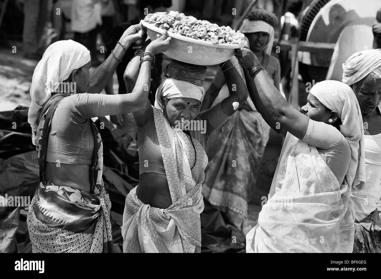 Le donne indiane lavorando sulle strade, sollevamento e trasporto di pietre in una ciotola sulla loro testa. Puttaparthi, Andhra Pradesh, India. In bianco e nero Foto Stock