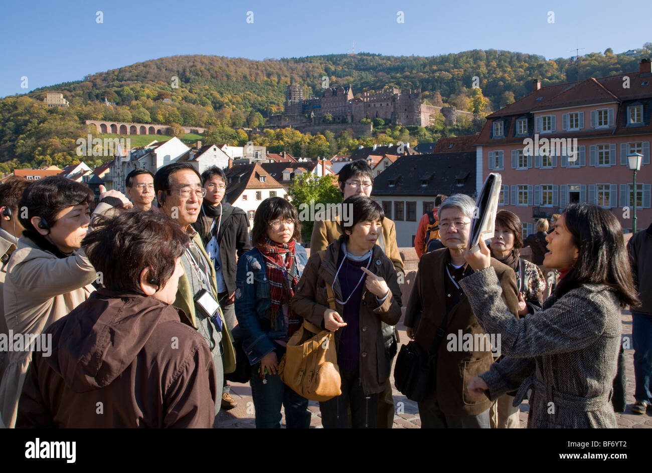 Il gruppo asiatico di persone con una guida turistica sul vecchio ponte di Heidelberg, Baden-Württemberg, Germania Foto Stock