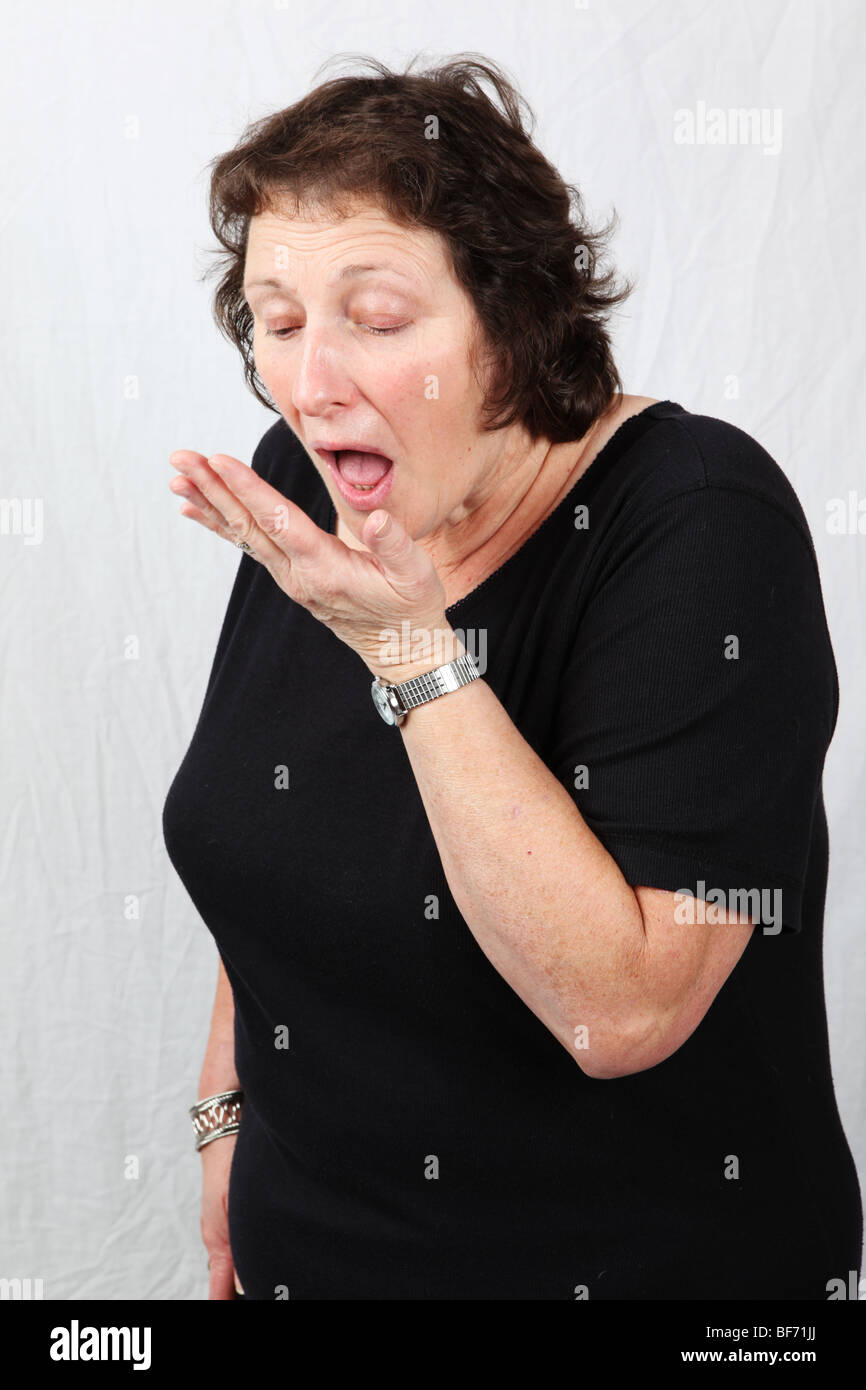 Ritardo medio di età compresa tra 50s 60s donna controllo alito cattivo tenendo la mano alla bocca che soffrono di alitosi gum infezione cattiva igiene orale Foto Stock