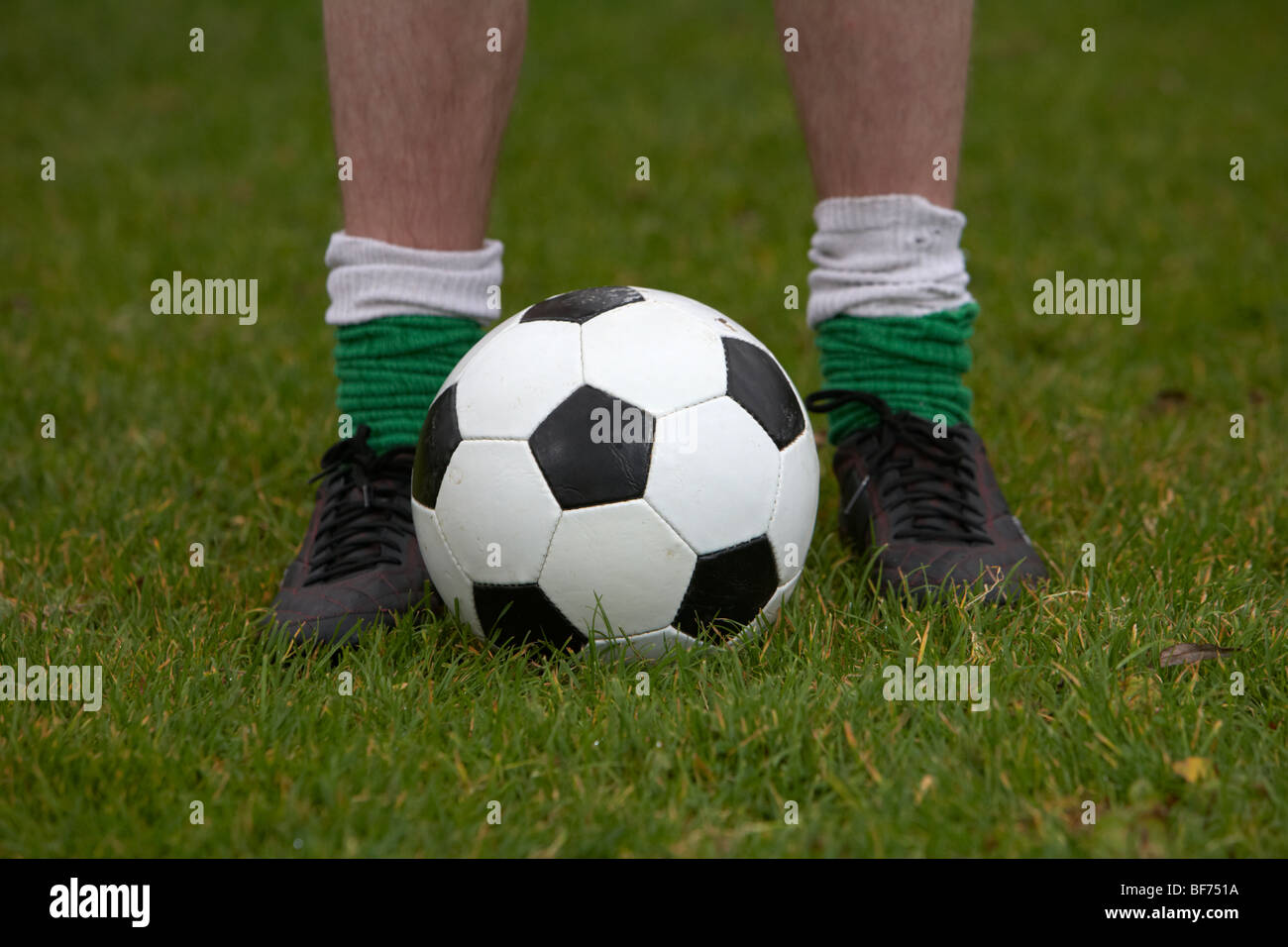 Soccer Football player in piedi con i piedi su entrambi i lati di una sfera Foto Stock