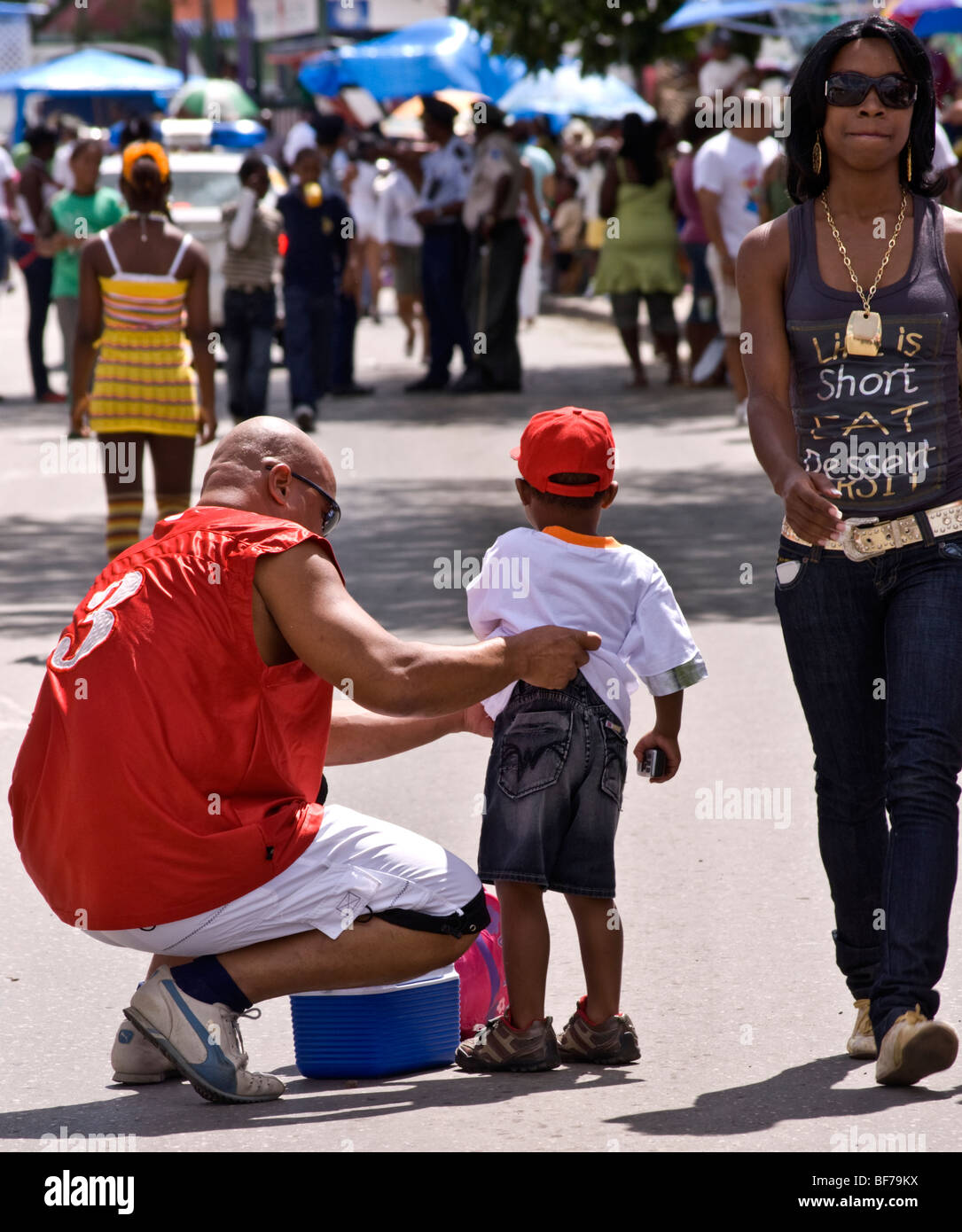 Padre aiuta il suo giovane figlio con le sue vesti circondato da spettatori alla sfilata di Carnevale Foto Stock