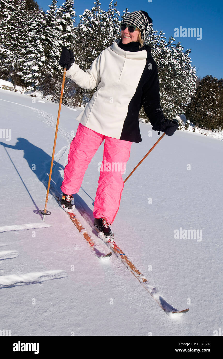 La donna in rosa pantaloni da neve fare sci di fondo su un lago