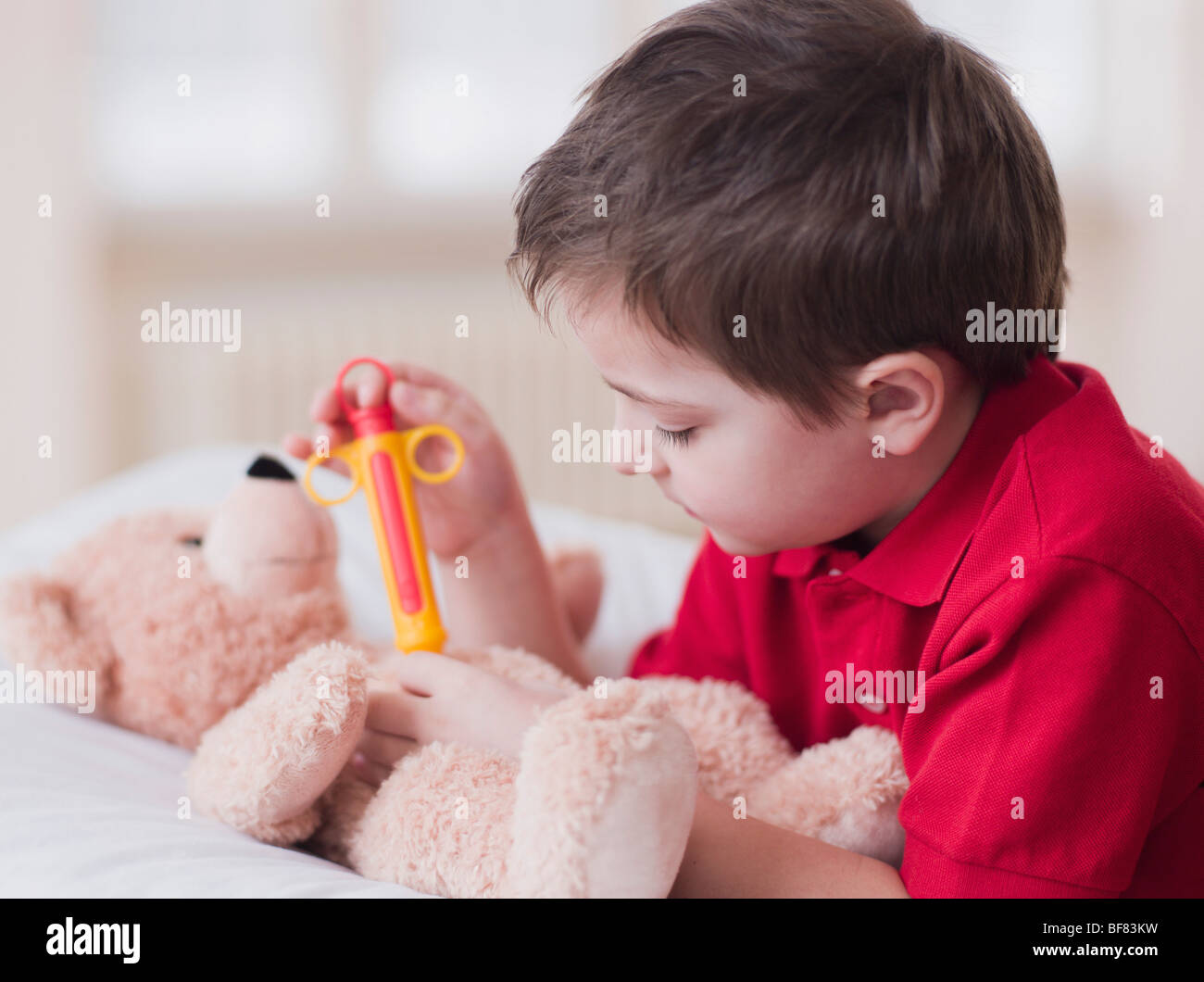 Ragazzo giocando con il giocattolo e orsacchiotto Foto Stock