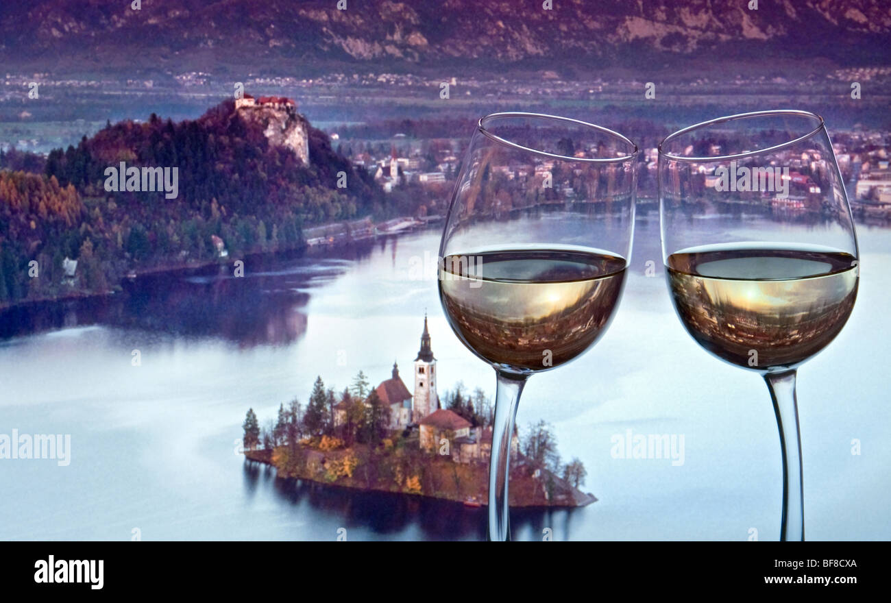 RISTORANTE CON VISTA SUL LAGO BLED, ROMANTICO bicchiere di vino bianco magro Tostatura ‘grazie’ con la chiesa dell’isola del lago Bled al tramonto Slovenia Europa orientale Foto Stock