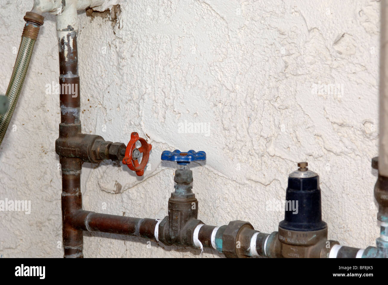 Plumbing residenziale che mostra un colore rosso principale della valvola di alimentazione e un blu split-valvola di intercettazione per l'irrigazione che conduce alla riduzione di pressione. Foto Stock