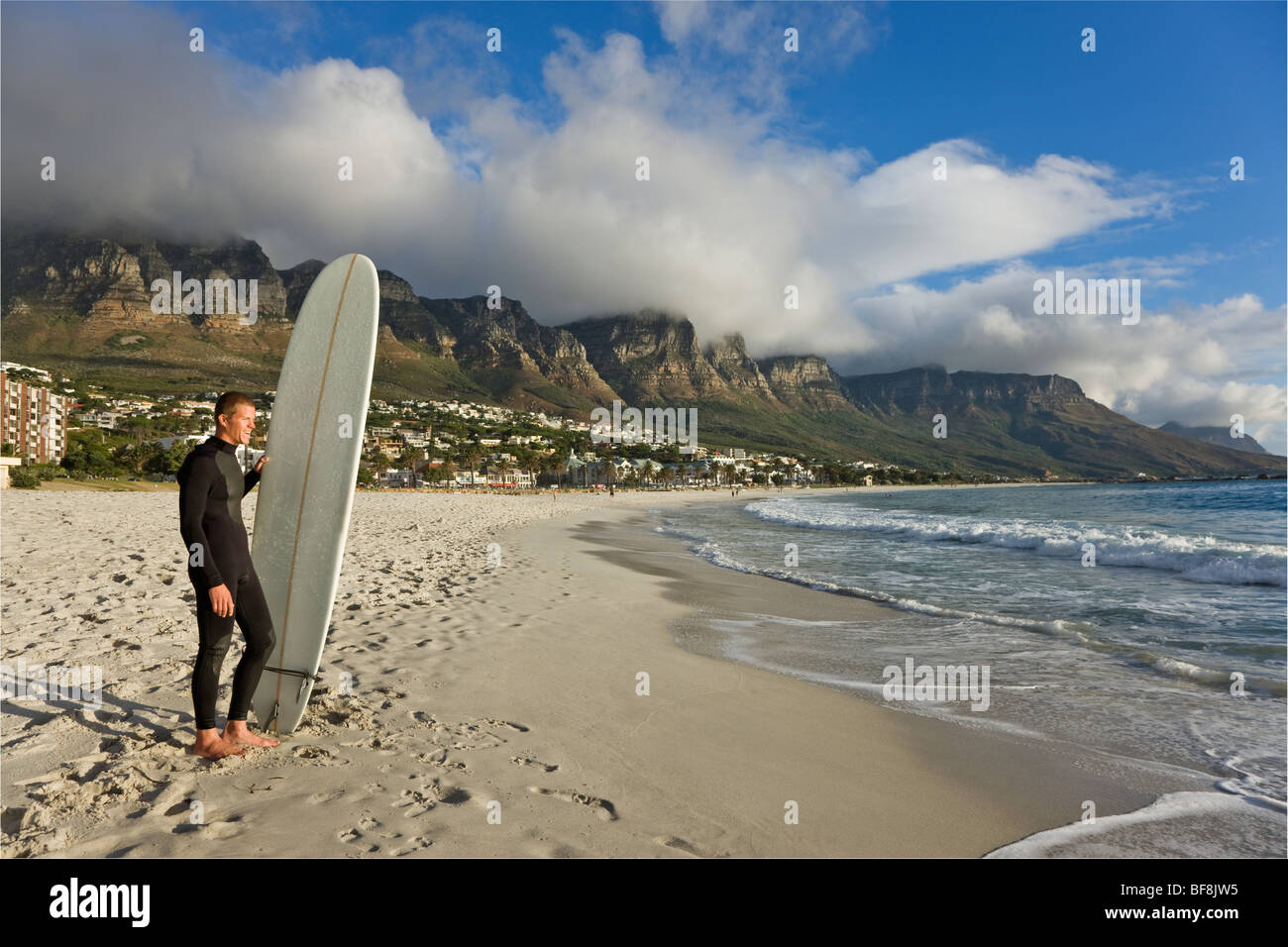 Surfer sulla spiaggia di Camps Bay con dodici apostoli di Table Mountain in background. Città del Capo Sud Africa Foto Stock