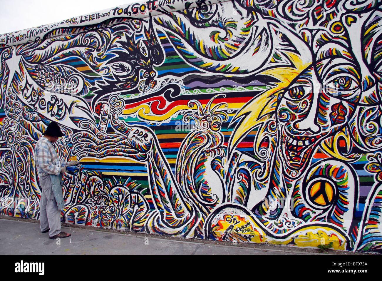 Un artista dipinge il muro di Berlino, all'East Side Gallery, a 1.3km-lungo la sezione della parete vicino al centro di Berlino Foto Stock