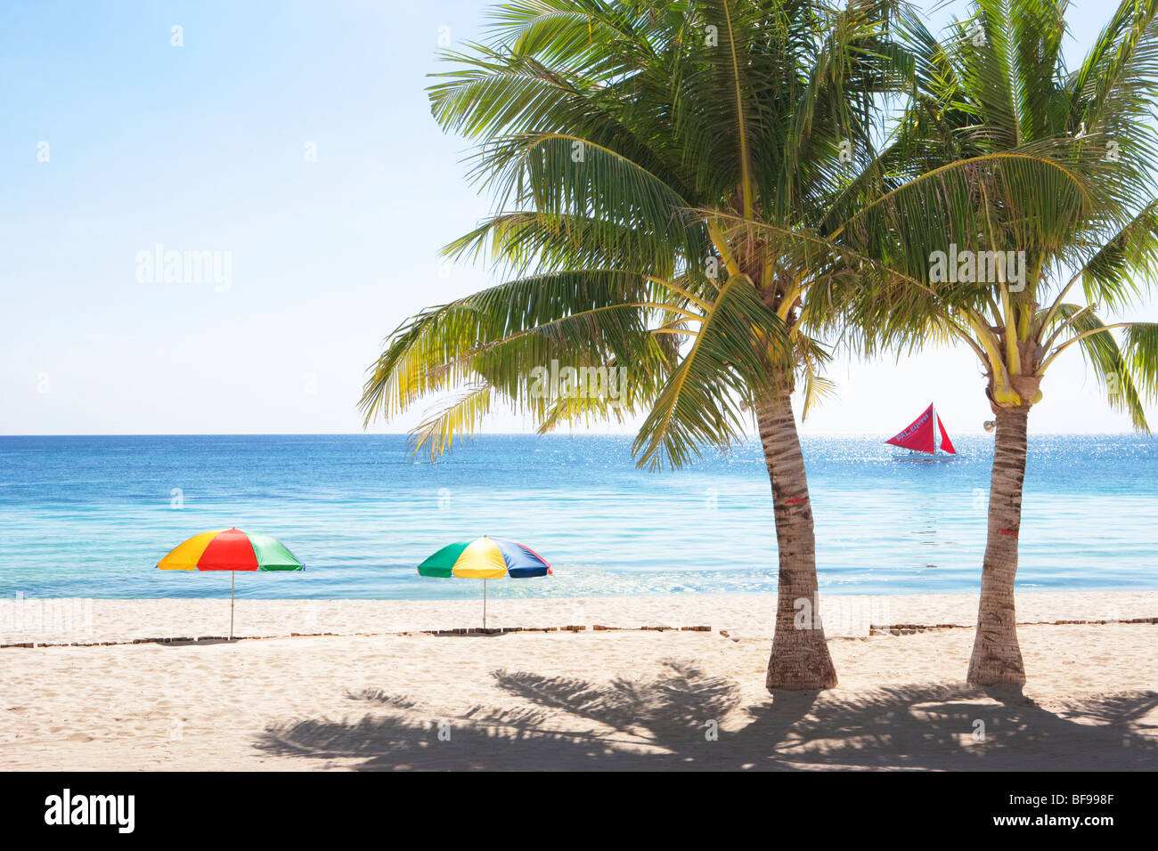 Spiaggia, palme, ombrelli, mare, sabbia e barche a vela in Boracay; Il Visayas; Filippine. Foto Stock