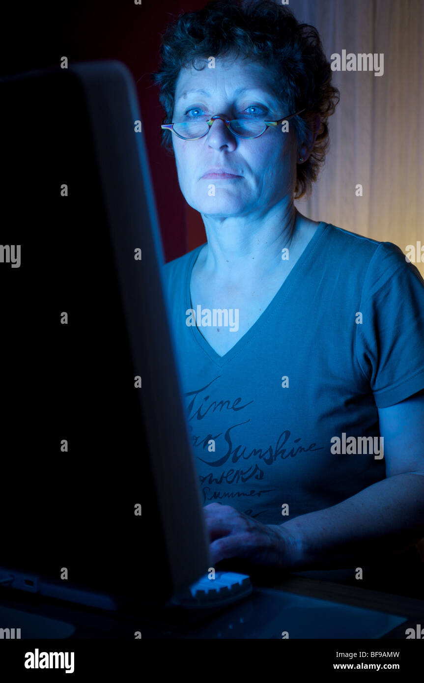 Donna che utilizza un computer di casa collegato a internet a tarda notte Foto Stock