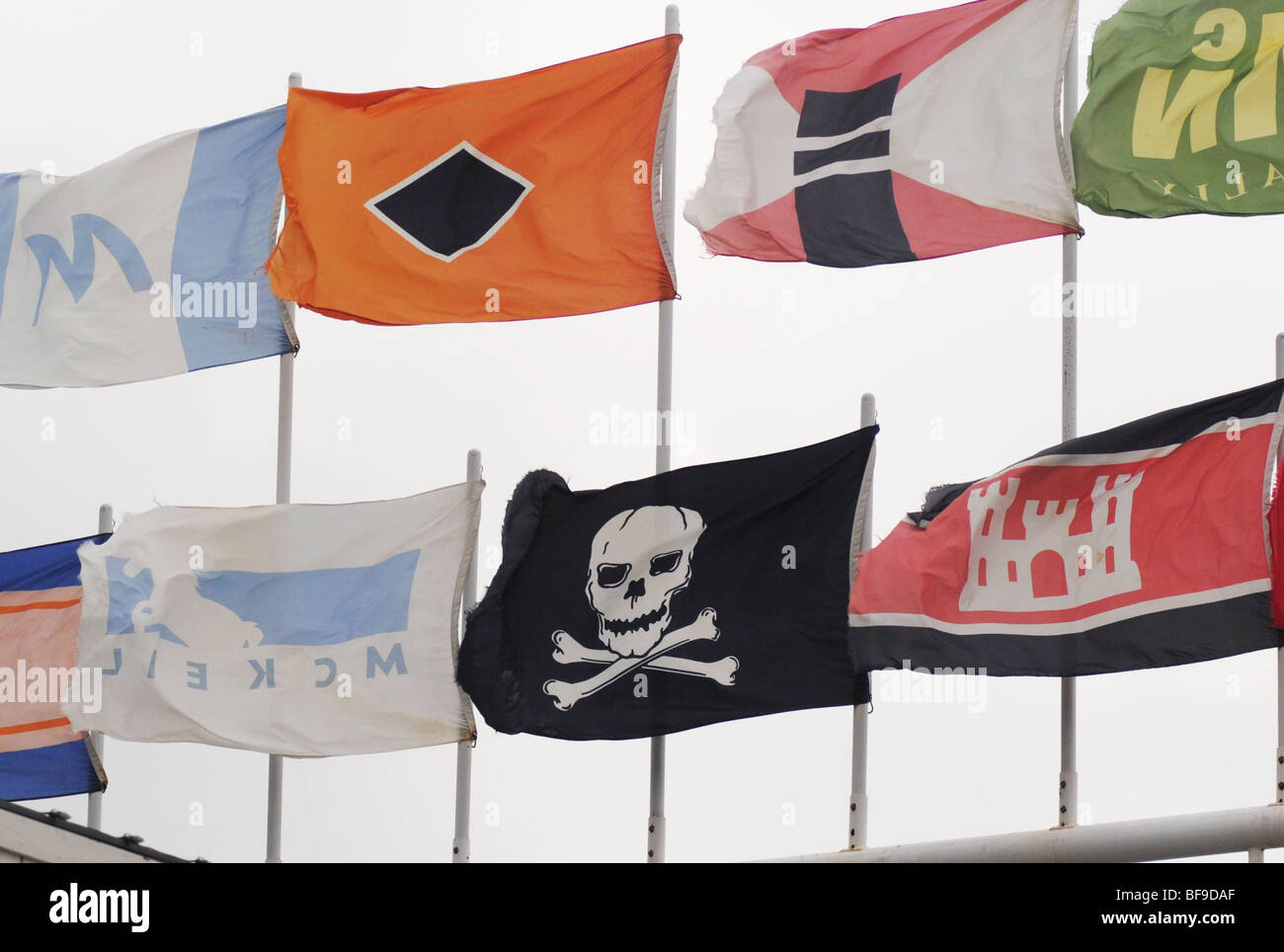 Il Jolly Roger, un pirata bandiera, vola con le bandiere marittime di compagnie di trasporto marittimo di una nave-guarda la struttura turistica Foto Stock