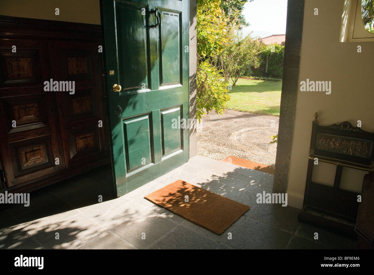Aperta la porta verde che si apre su un giardino in una giornata di sole Foto Stock