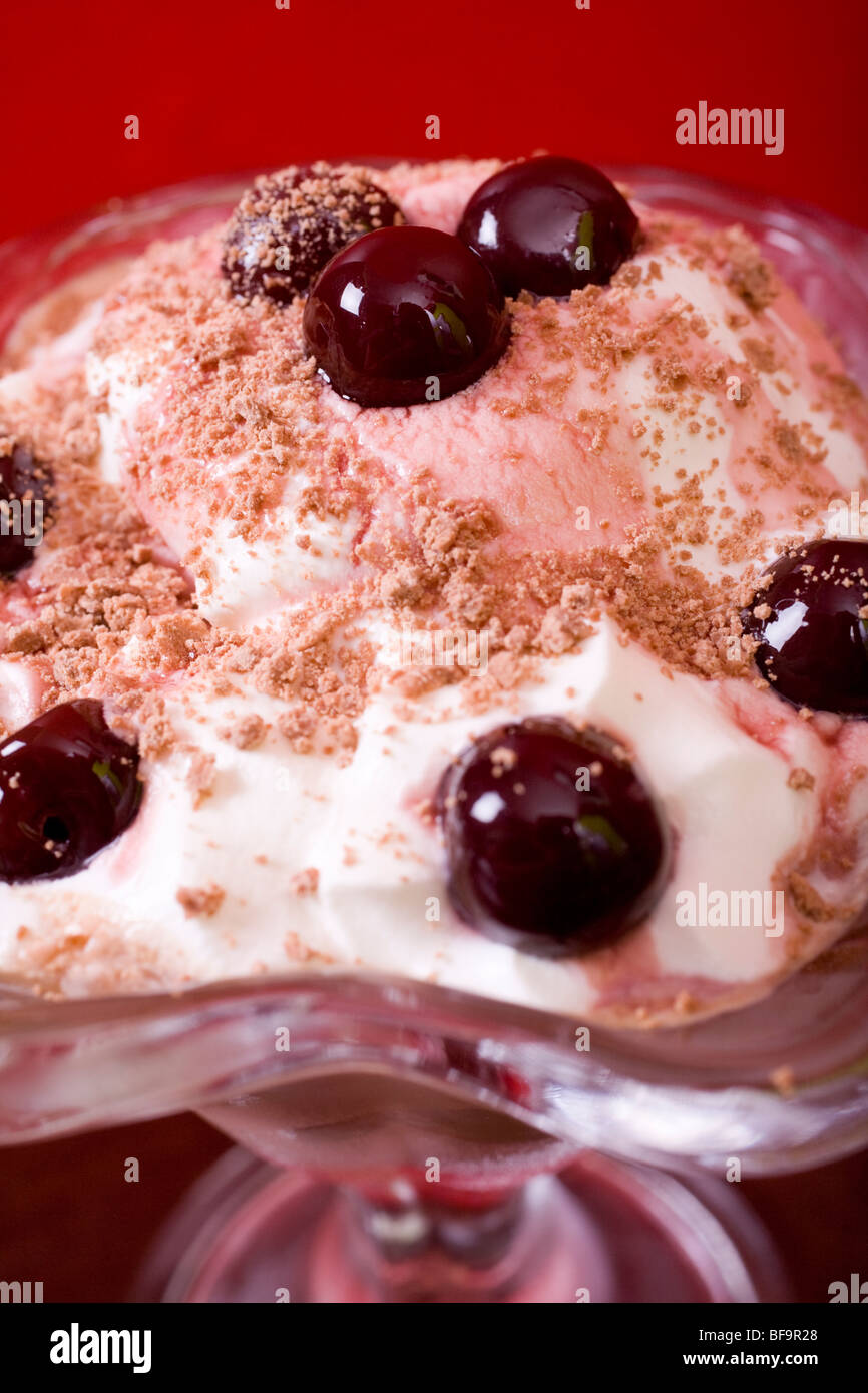 Cioccolato gelato Gelato con scaglie di cioccolato e una ciliegia vetrata sulla parte superiore, servita in una graziosa di vetro. Foto Stock
