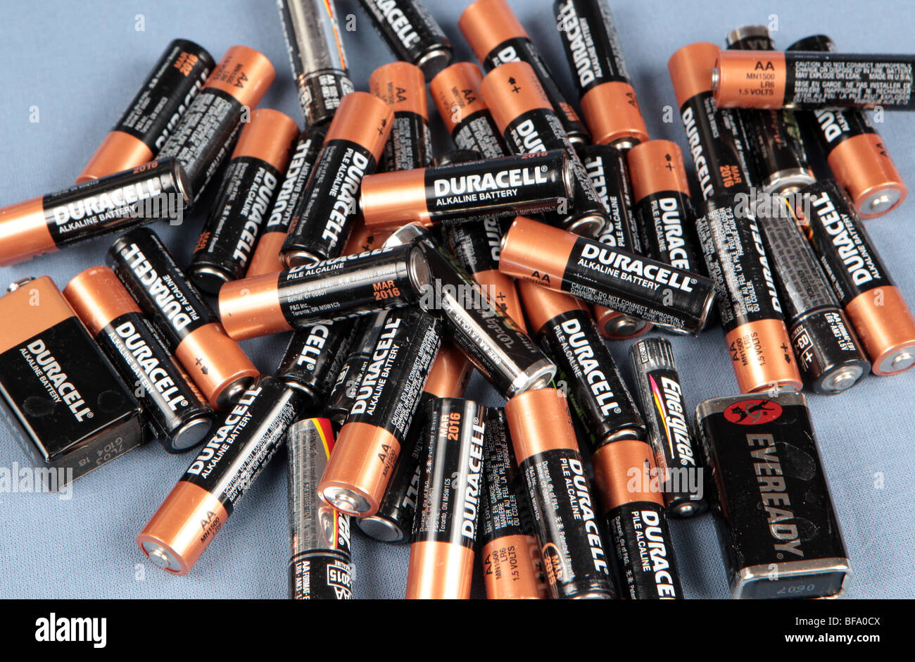 Una pila di batterie AA impilati su un tavolo girato contro uno sfondo blu.  Le batterie usate pronto per il riciclaggio Foto stock - Alamy