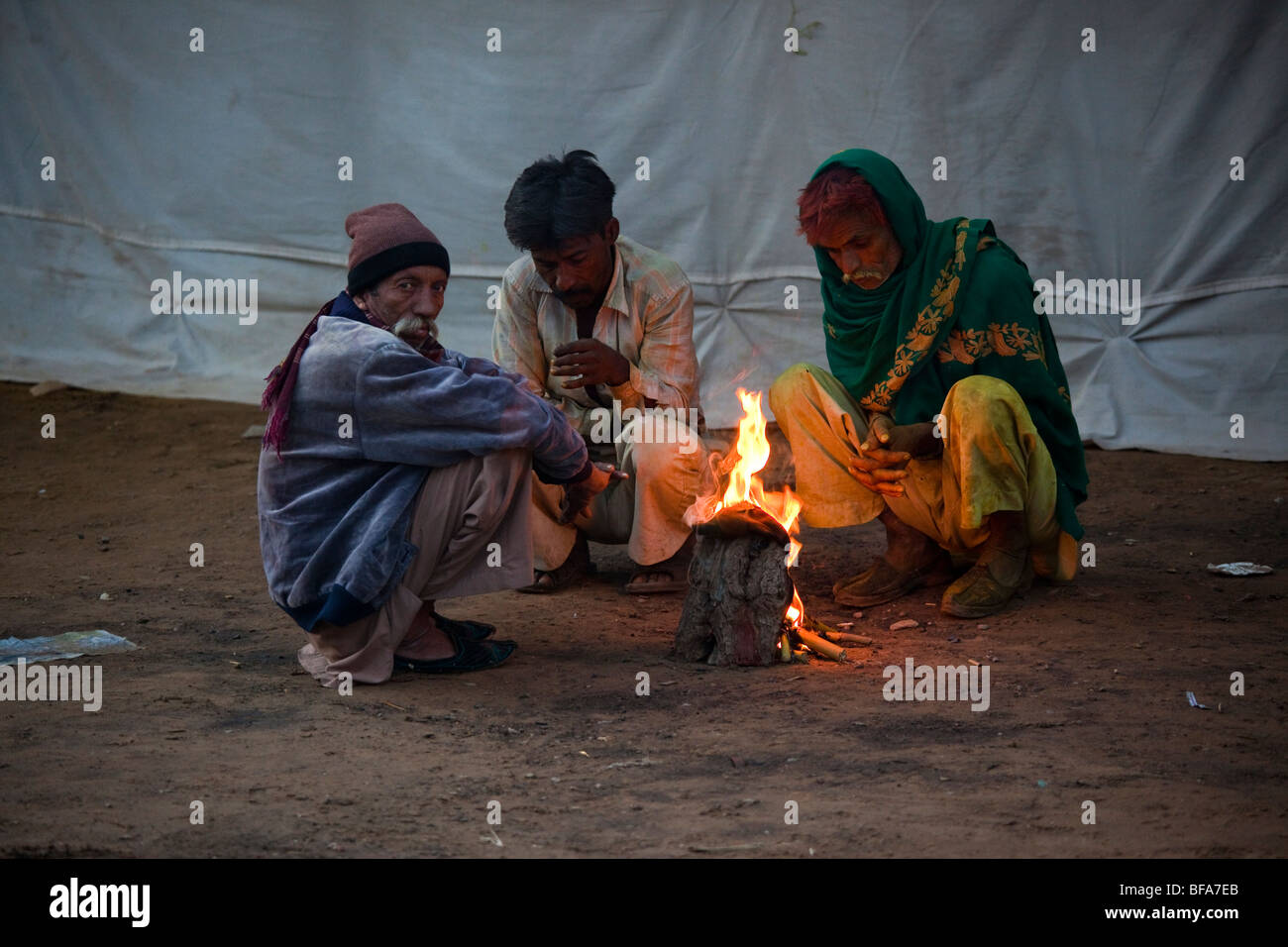 Indian uomini intorno a un piccolo incendio presso il Camel festival di Pushkar India Foto Stock