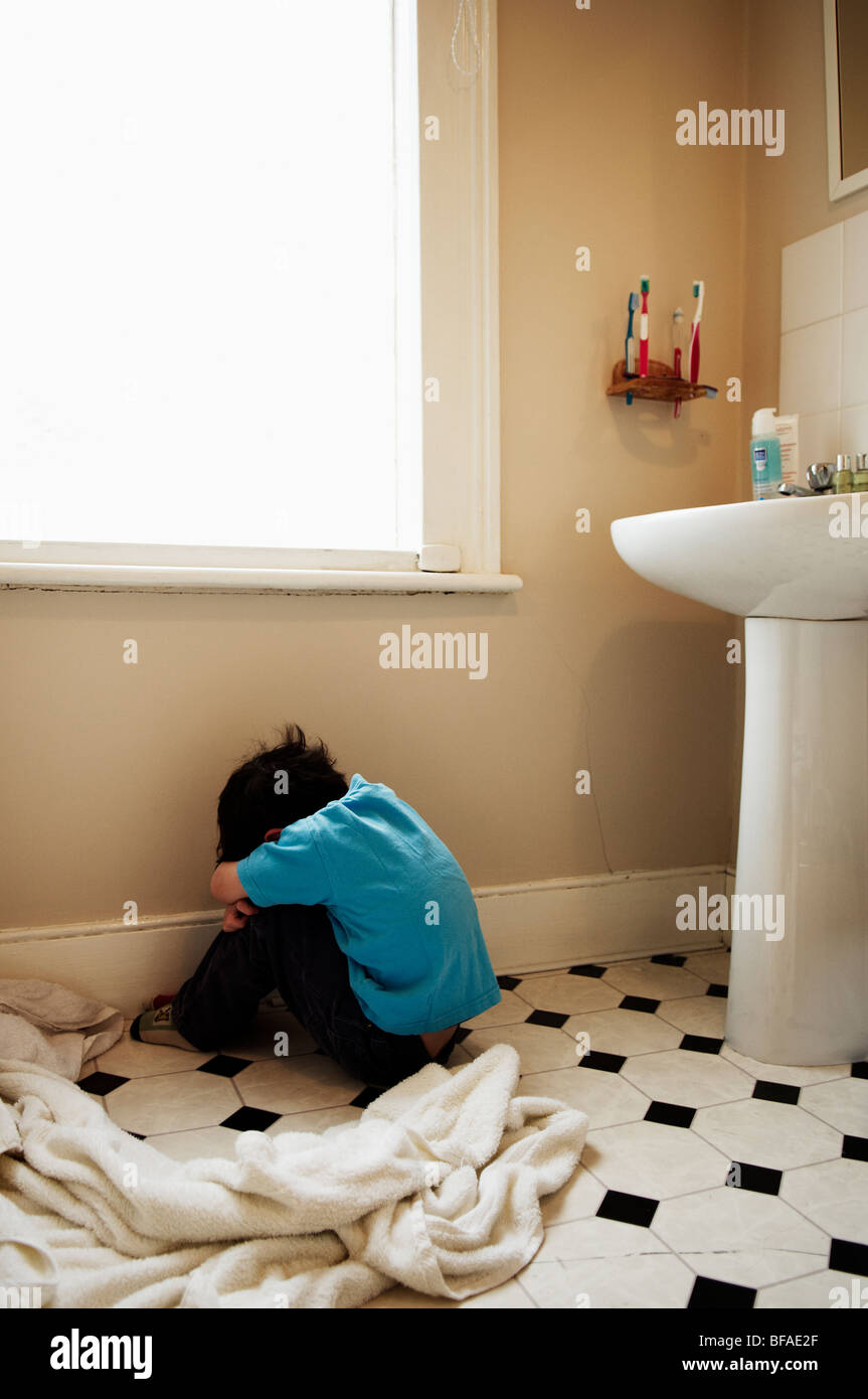 Un ragazzo sconvolto si siede sul pavimento del bagno con la schiena  rivolta alla telecamera Foto stock - Alamy