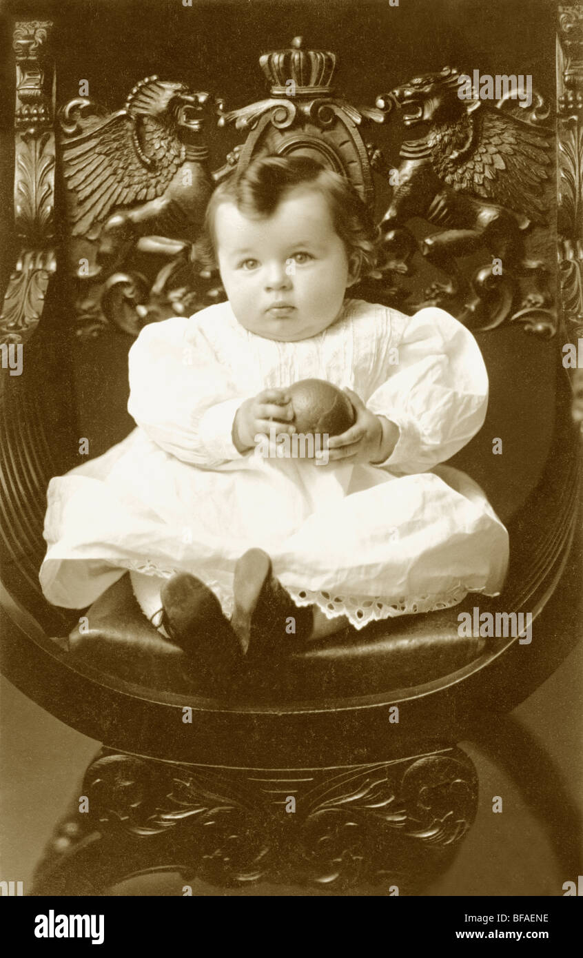 Adorabili neonati con sfera in trono sedia Foto Stock