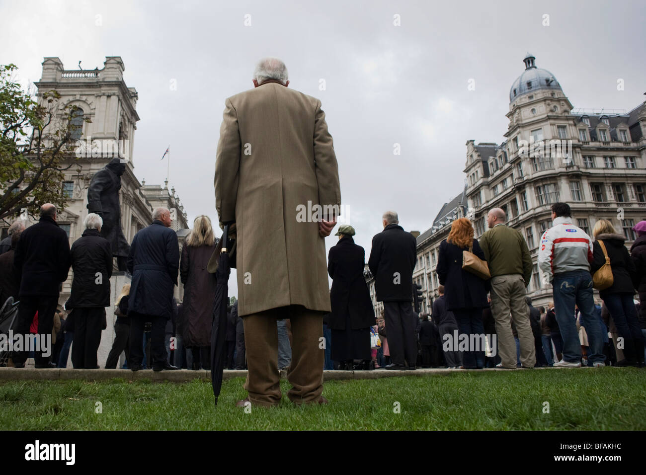 Sotto Winston Churchill della statua, la folla stand solennemente per due minuti di silenzio in piazza del Parlamento su un ricordo Domenica. Foto Stock