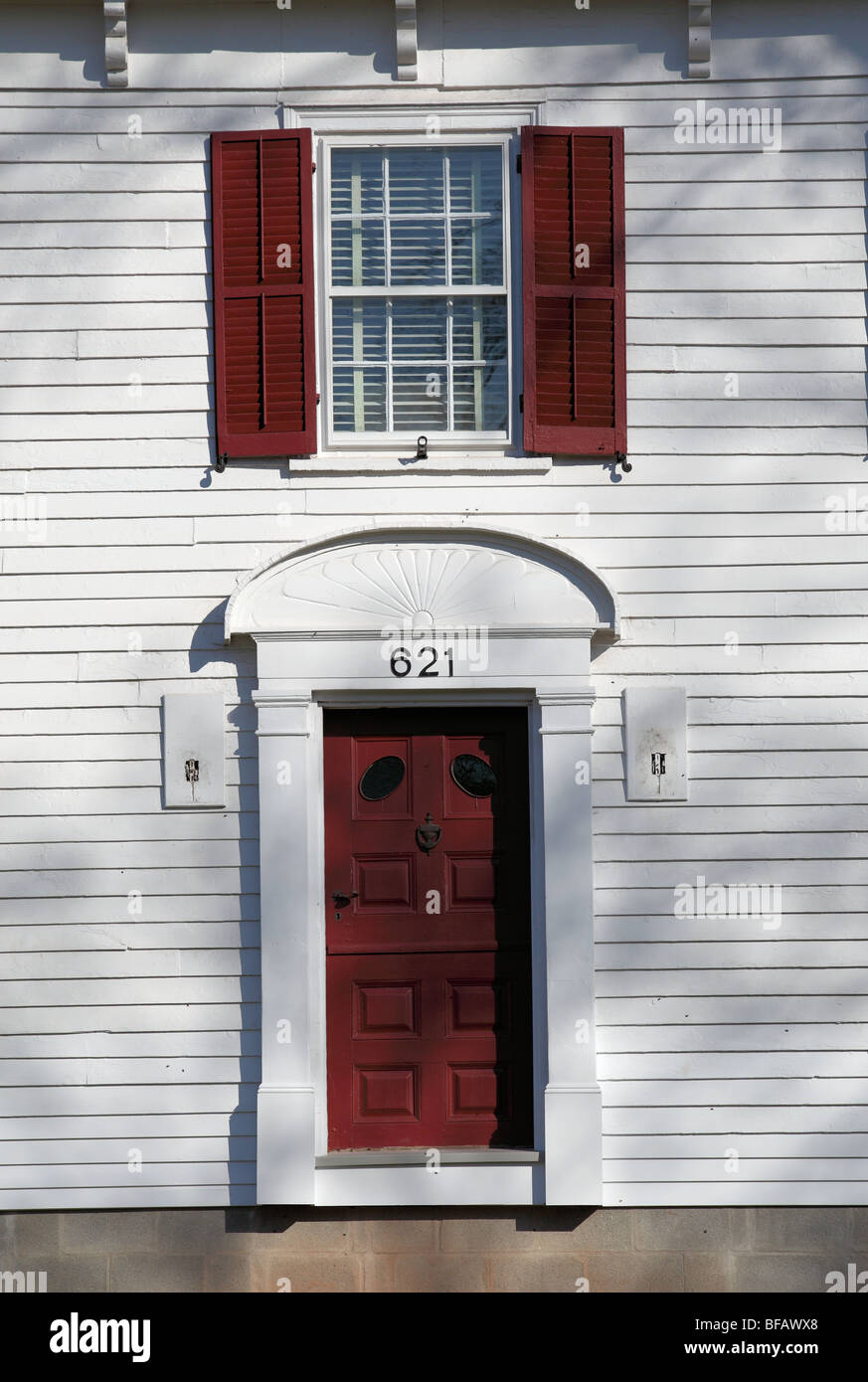 Bianco casa coloniale con red persiane in legno. Foto Stock