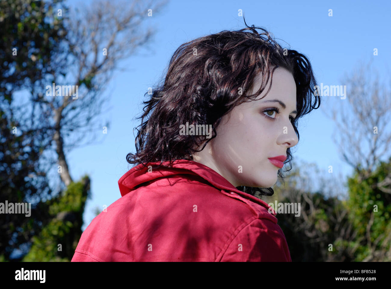 Giovani dai capelli scuri brunette donna fuori, guardando sopra la sua spalla. Foto Stock