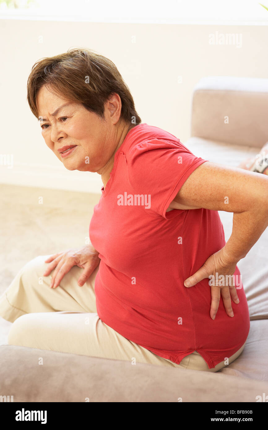 Senior donna che soffre di dolori alla schiena a casa Foto Stock