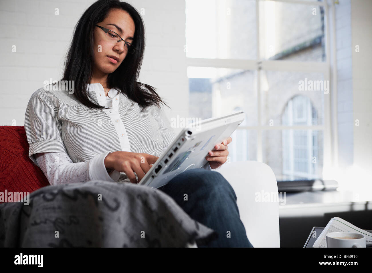 Una donna usa un tablet PC in una luminosa ambiente casalingo, Foto Stock