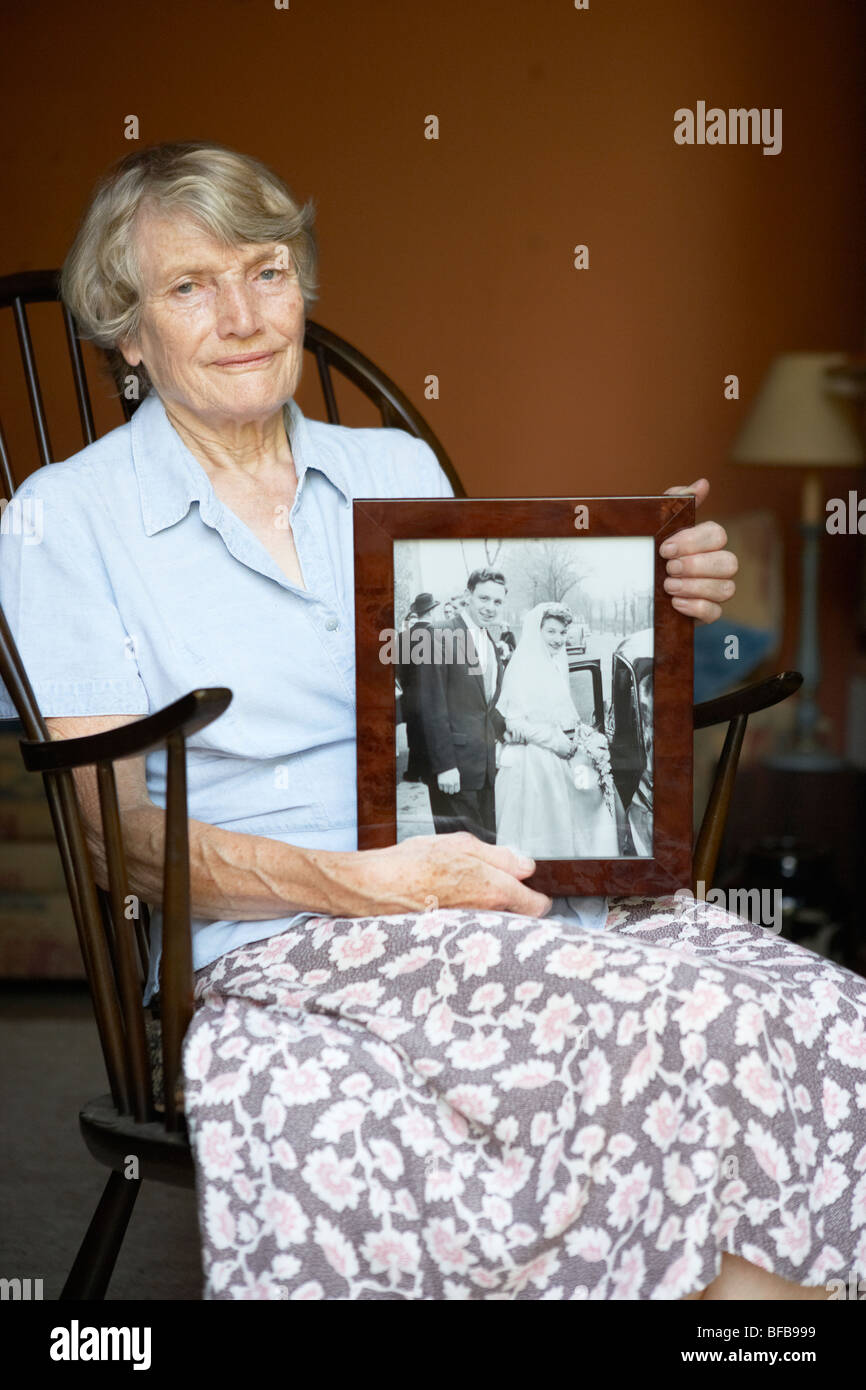 Senior donna a casa guardando vecchi Wedding Photo Foto Stock