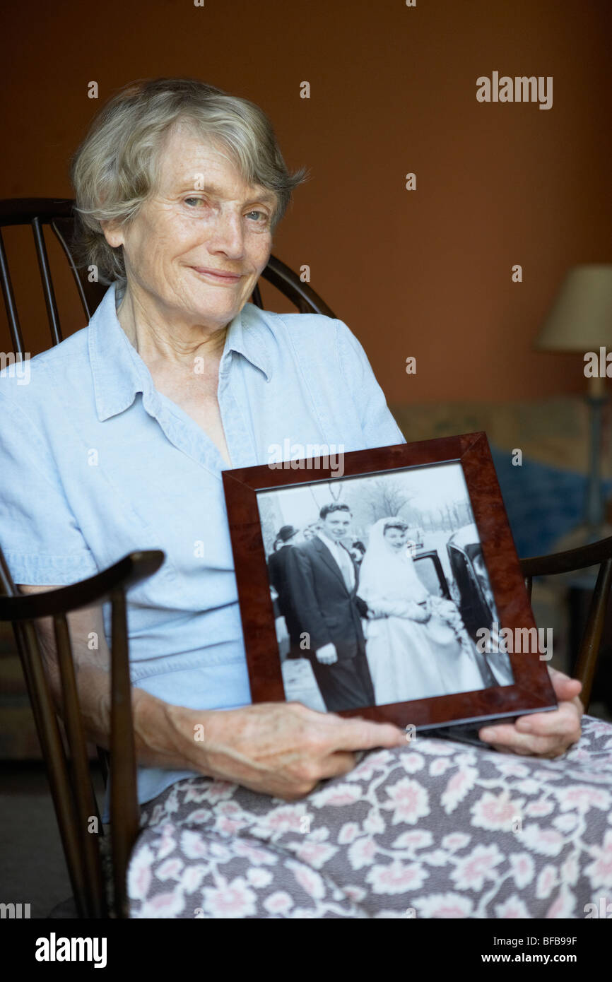 Senior donna a casa guardando vecchi Wedding Photo Foto Stock