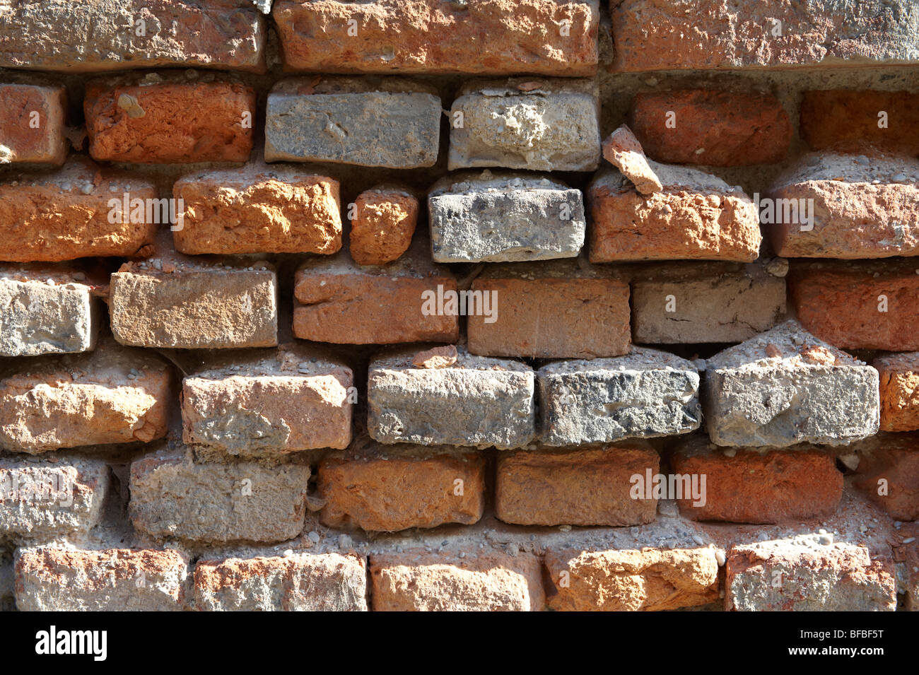 Primo piano di vecchio muro di mattoni rossi con mattoni danneggiati, texture urbane Foto Stock
