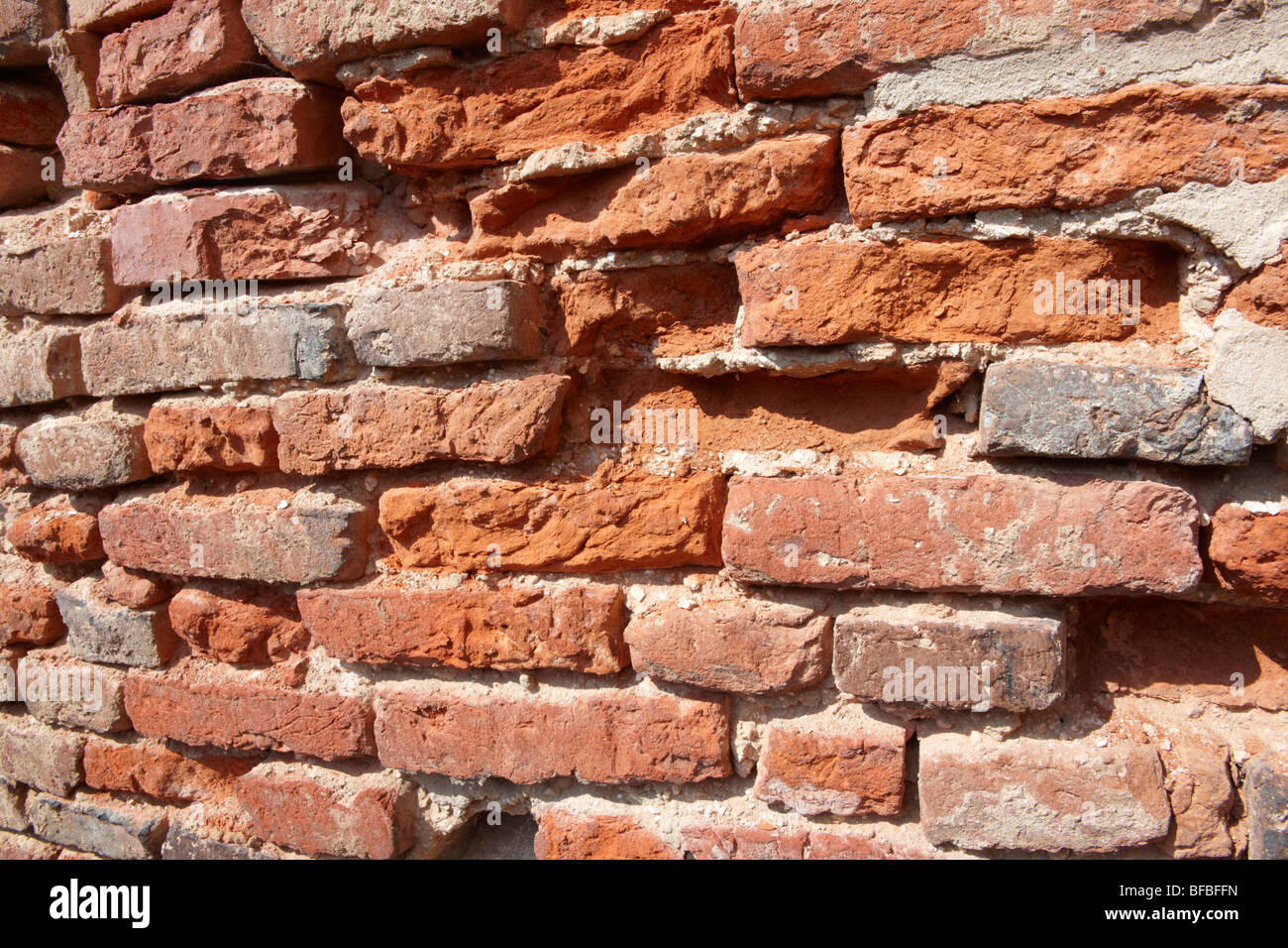 Primo piano di vecchio muro di mattoni rossi con mattoni danneggiati, texture urbane Foto Stock