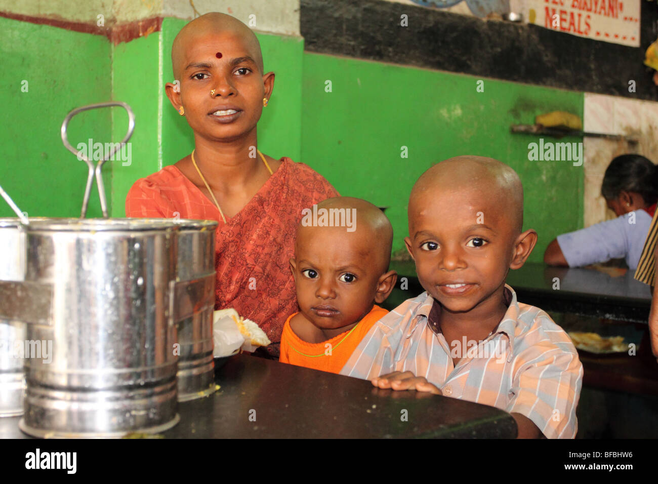 Madre e figli in attesa a Tirupati alla stazione degli autobus, dopo aver visitato il tempio Tirumala per offrire i loro capelli agli dèi. Foto Stock
