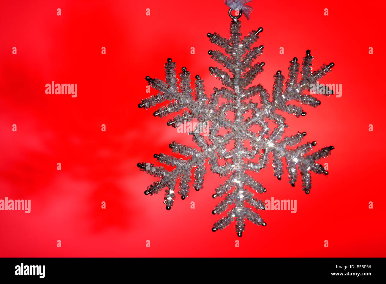 Glittery il simbolo del fiocco di neve decorazione di Natale contro uno sfondo rosso Foto Stock